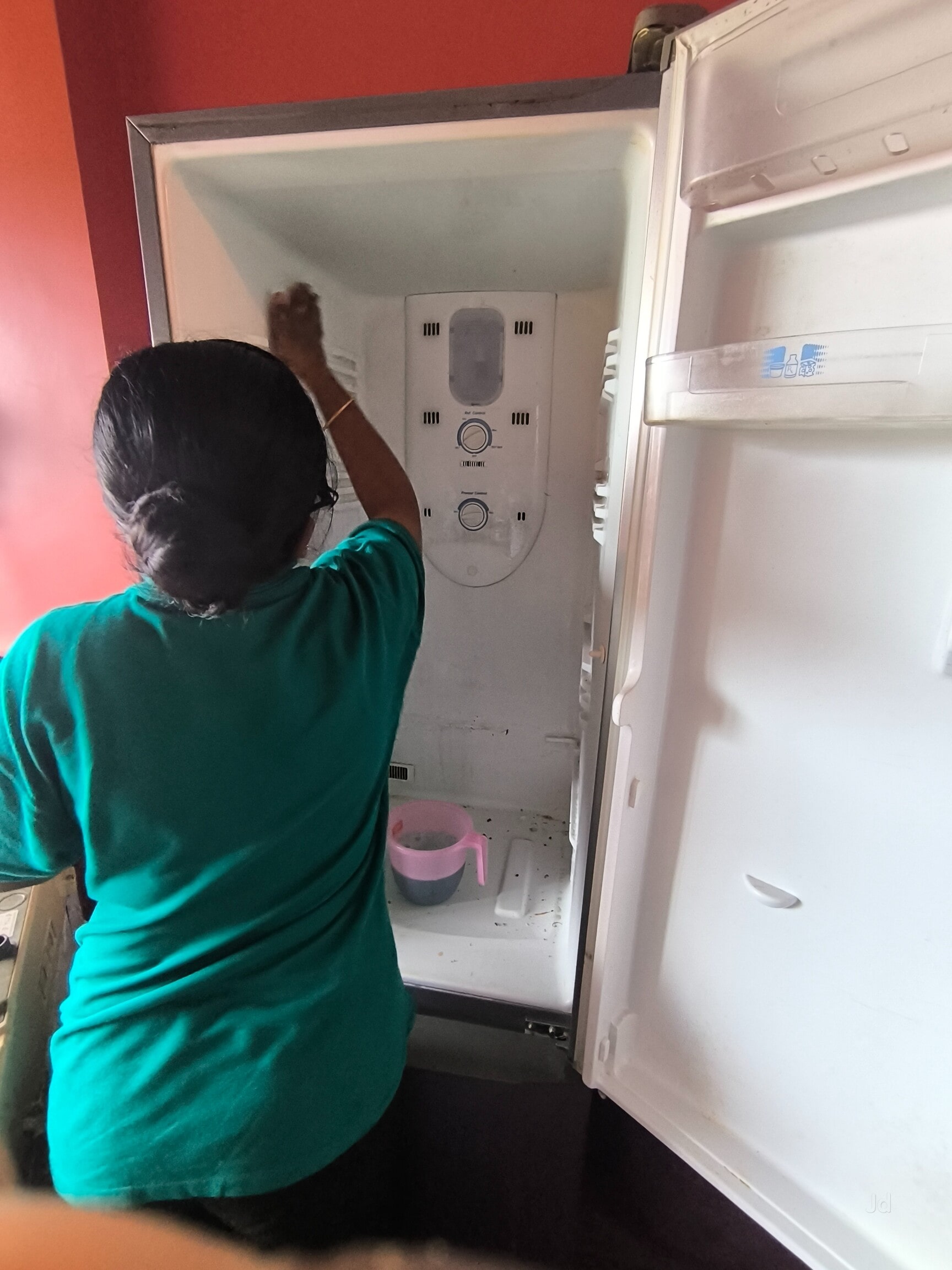 Staff member deep cleaning the inside of a refrigerator